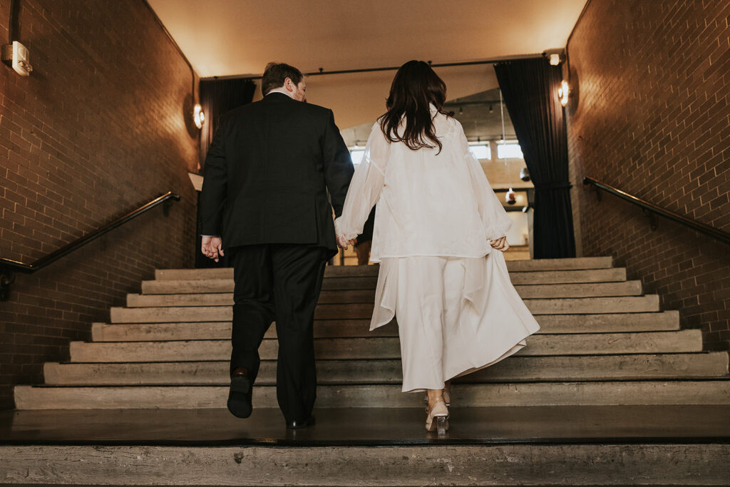 the back of a dressed up couple, walking up the stair at Central Station in Memphis, TN for engagement photos