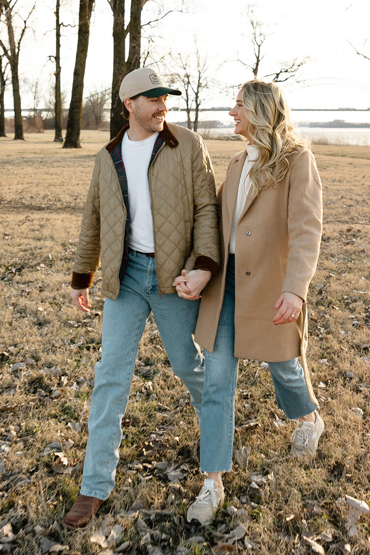 couple dressed in winter attire and holding hands, while walking on Mud Island in Memphis, TN for engagement photos