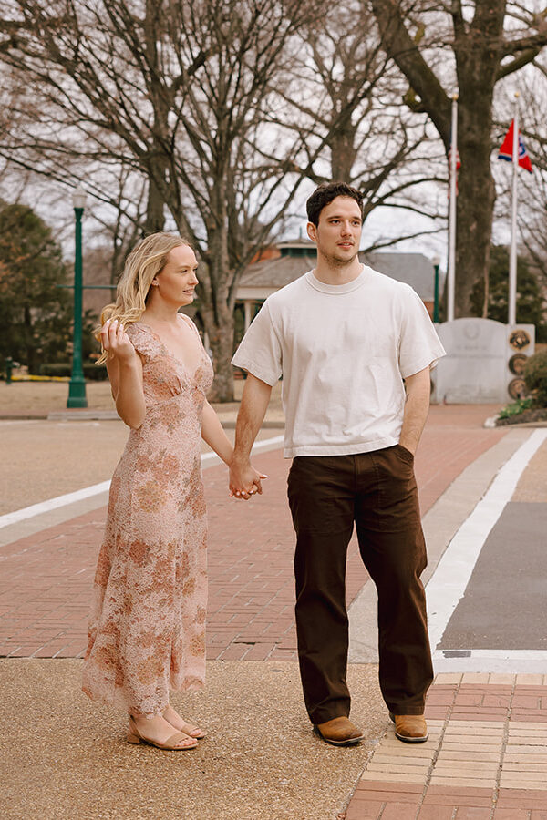 engaged couple holding hands near the side of the street for engagement photos